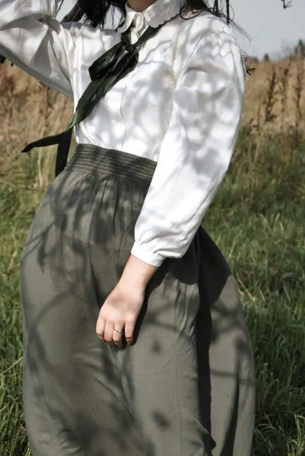 Woman wearing long black skirt and elegant white blouse.