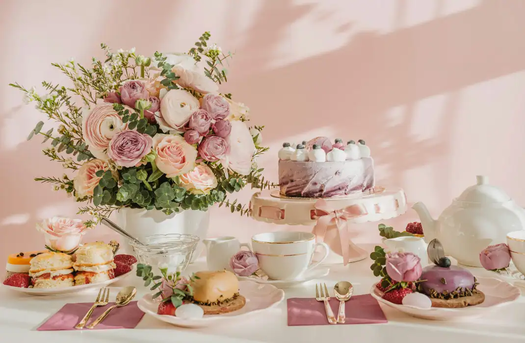 tea pot and cups surrounded by cake, flowers, and treats