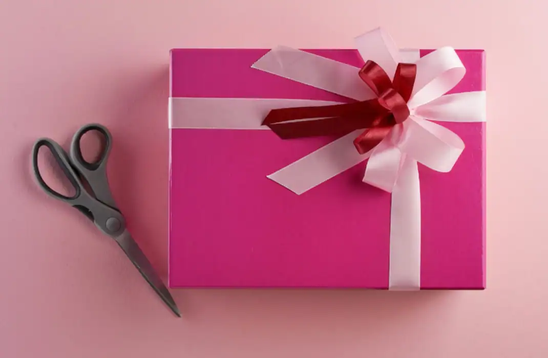 pink gift box with white and red ribbon