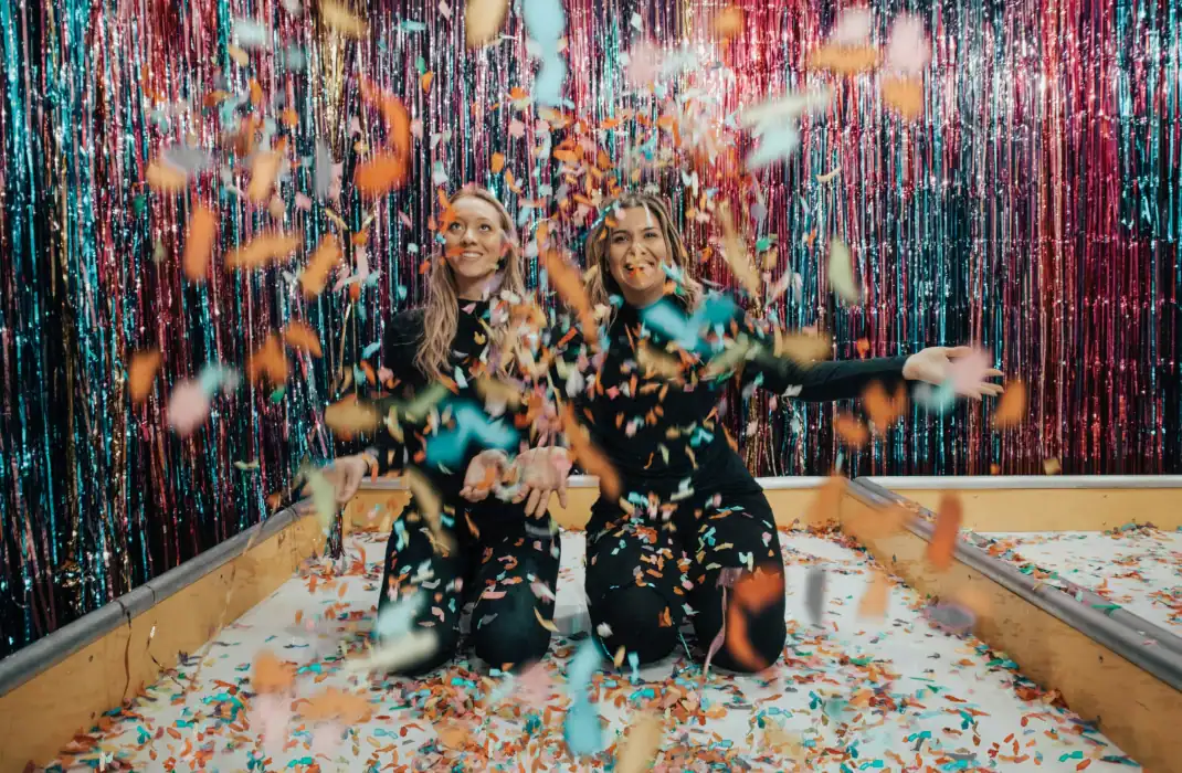 women having fun surrounded by glitter wall